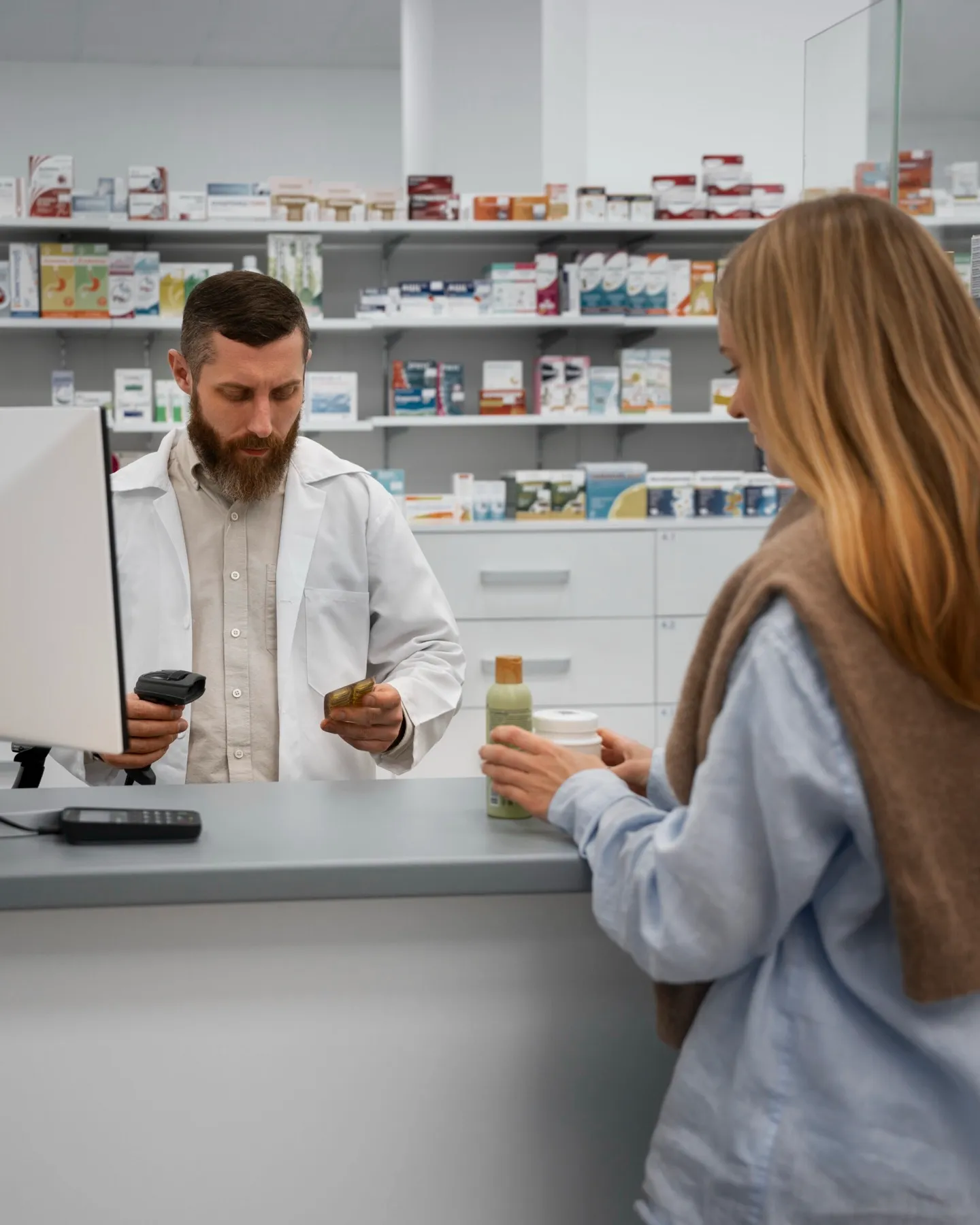 A pharmacist talks with a customer while holding a prescription bottle