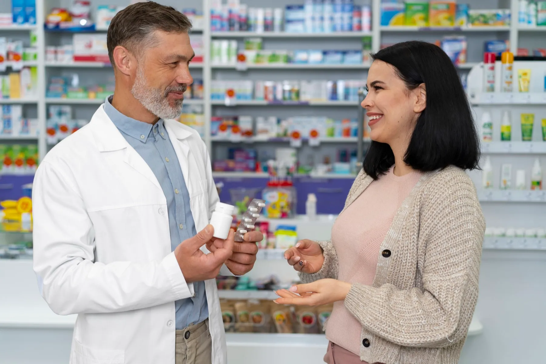 A pharmacist helps a smiling patient at the pharmacy counter